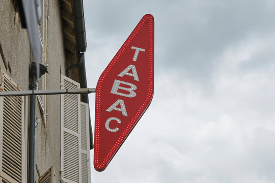 Slanted diamond-shaped red signboard with the word tabac in white and neon above a shop in Saint-C&eacute;r&eacute; Lot Occitanie Southern France. Tabac means tobacco in English