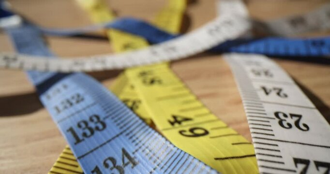 Sewing tapes measure with different metric types on wooden table in atelier. Dressmaker tools on desk in workshop. Manual tailor instruments