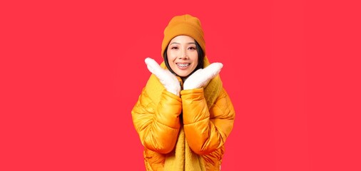 Young Asian woman in winter clothes on red background