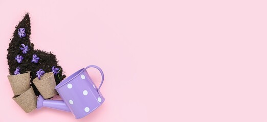Watering can, pots, soil and flowers on pink background with space for text
