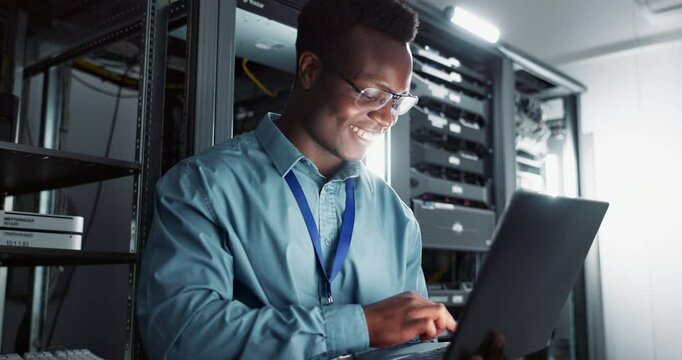 Happy man, technician and laptop in server room for database update, cyber security or code. Computer, smile and African engineer in data center for information technology, typing and programming