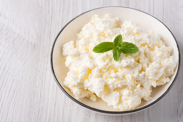 Cottage curd cheese in a wooden bowl on white background. Homemade milk food