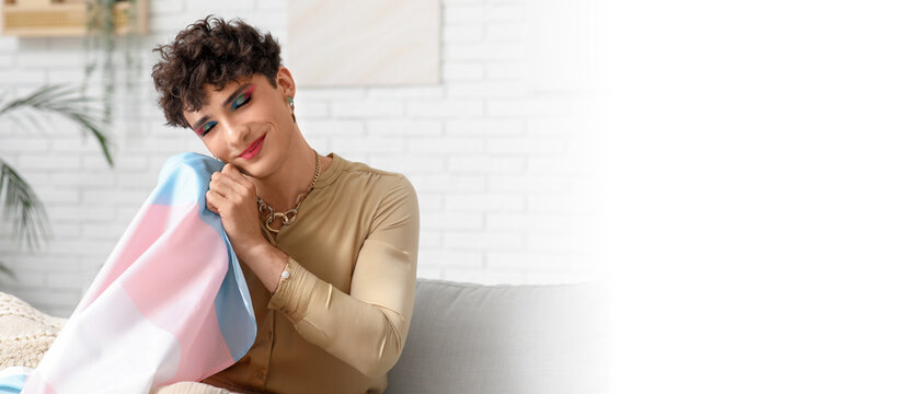 Young transgender woman with flag sitting on sofa at home. Banner for design