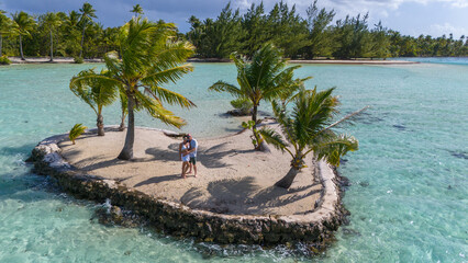 Aerial view captured by drone. Middle aged couple spending a romantic day together on a heart shaped motu near the tropical island of Taha'a in French Polynesia. 