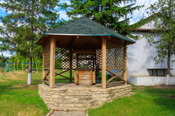 A wooden pavilion with a roof and a small table, rural well