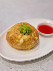 Crab omelet decorated with coriander leaves and chili sauce on white plate, Thai food.	