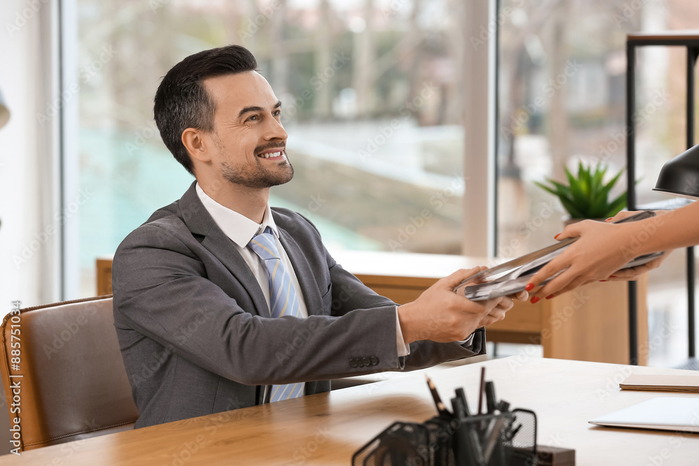 Wall mural handsome businessman taking folder from secretary at table in office