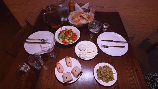 Georgian cuisine, food in restaurant. Traditional Georgian food Adjara on table. Homemade cakes. View from top. Flat laying. Jonjoli, Pkhali, Tadugi, Wine and Bread.