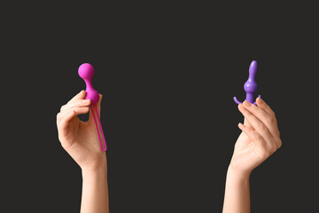 Female hands with sex toys on dark background, closeup