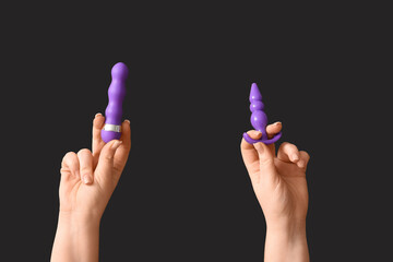 Female hands with sex toys on dark background, closeup