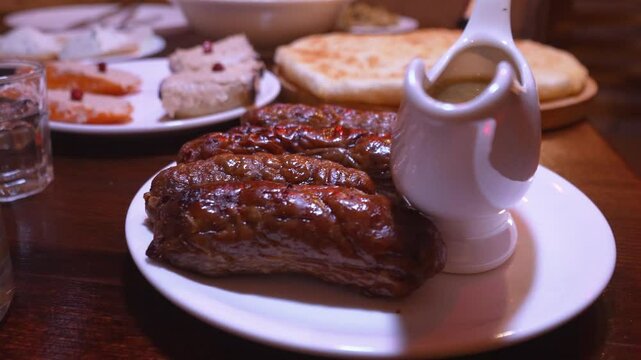 Sausages and kupat kupati, homemade sausage Traditional Georgian dish on Georgian traditional table in restaurant with tkemali sauce on plate. Georgian food in restaurant.