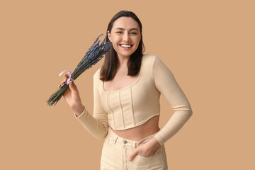 Beautiful happy young woman with bouquet of lavender flowers on beige background