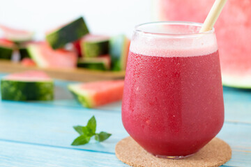 Watermelon smoothie glass with mint on wooden table. Close-up. Cold red summer drink, healthy fruit shake.