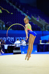 Female gymnast in colorful leotard performs with a hoop, displaying skill and grace at a competition