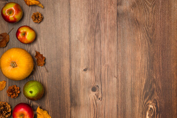Autumn harvest. Pumpkin, pears, apples, pine cones, and leaves on wooden background. Copy space, top view