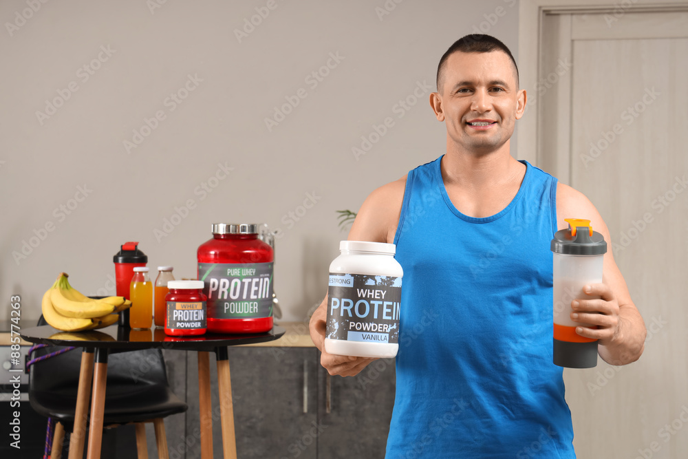 Wall mural sporty muscular man with protein powder and shake in kitchen