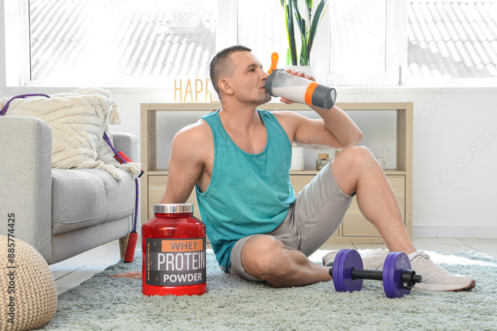 Sticker Sporty muscular man drinking protein shake on floor at home