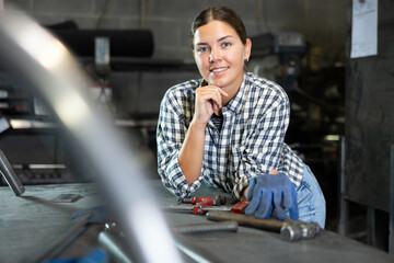 Young female factory worker posing in metallurgical workshop