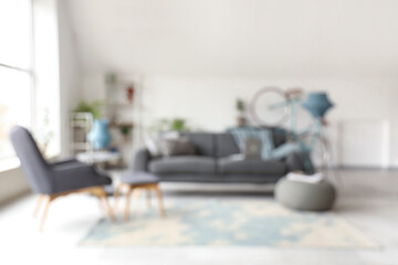 Stylish interior of white living room with sofa and armchair, blurred view