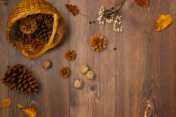 Basket with cones and nuts on wooden background. Autumn composition. Top view, flat lay