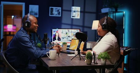 Content creator enjoying nice conversation with guest during podcast. Host enjoying coffee together with cheerful woman live in apartment studio during internet show, zoom out shot