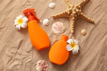 Bottles of sunscreen cream, starfish and flowers on sand