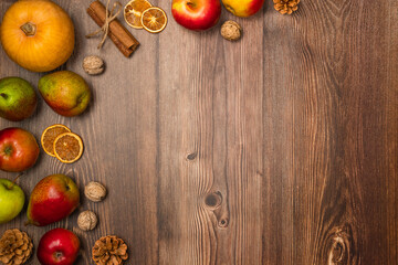 Autumn harvest. Pumpkin, pears, apples, nuts, pine cones and cinnamon on wooden background. Copy space, top view