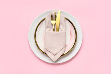 Beautiful table setting with golden cutlery on pink background
