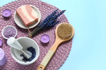 Beautiful composition with lavender in mortar, wicker mat and candles on blue background