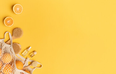 Fresh oranges and brushes in a eco bag. Essential oil in a glass bottle for massage. Yellow background