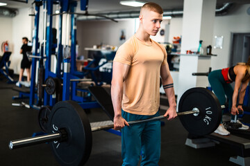A male bodybuilder performs a weightlifting exercise in a gym