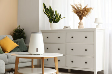 Modern humidifier on coffee table near chest of drawers in stylish living room