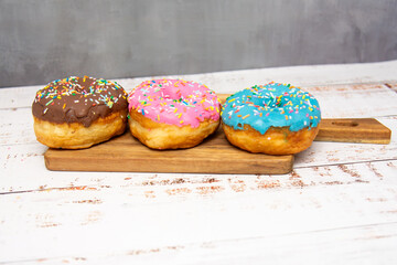 Delicious dessert. Pink, blue and chocolate donuts with multicolored sprinkles.