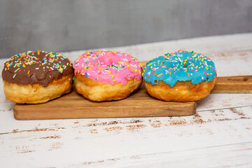 Delicious dessert. Pink, blue and chocolate donuts with multicolored sprinkles.