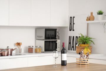 Glass, bottle of wine and openers on wooden table in kitchen