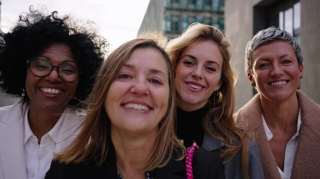 Happy empowered worker diverse business only women looking cheerful at camera together with nice expression outdoors. Mature Caucasian professional formal female leader posing joyful in close-up