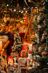 Festively decorated store window, in the center of the display is a Christmas tree strung with colorful lights and ornaments. There are wrapped gifts in various sizes