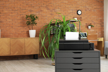 Modern printer on chest of drawers in office