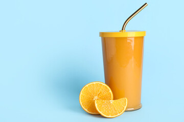 Glass of healthy orange juice on light blue background