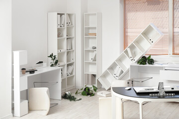 Interior of messy office with overturned furniture and houseplants after earthquake