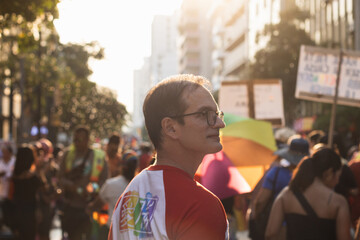 Portrait of adult man marching in the LGBT pride march wearing a Pride Day t-shirt, looking at his...