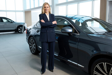 Female sale assistant in elegant suit in a car showroom