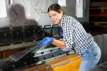 Metallurgical plant - female worker bending sheet of metal on a press