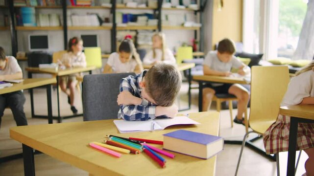 A sad elementary school student in a blue plaid shirt is being fussy, crying, and refusing to learn