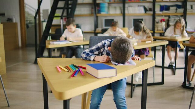 A sad elementary school student in a blue plaid shirt is being fussy, crying, and refusing to learn