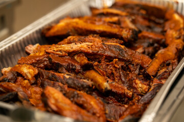 Grilled BBQ ribs in a tin container to be server at an event. Party catering ribs. 