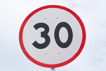 Speed limit sign is on sky background.Maximum speed is 30.