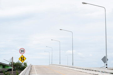 Speed limit sign and  Two-way traffic ahead sign are on left side of U-turn bridge.