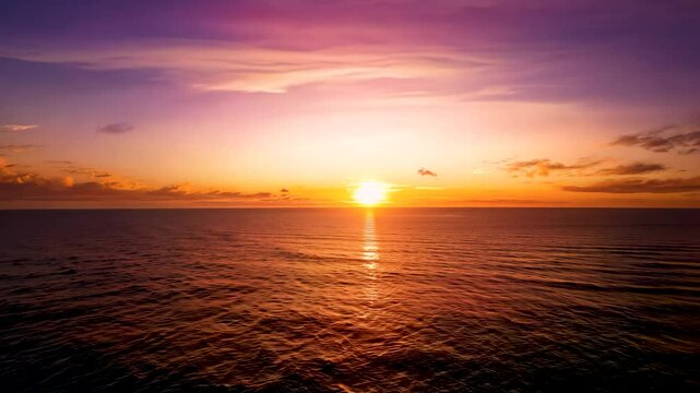 Timelapse of sunset over ocean with vibrant hues, capturing the serene beauty as the sun sets below the horizon.
