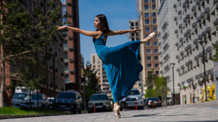 Beautiful Asian ballerina in blue dress dancing outdoors. Urban landscape. © Михаил Решетников